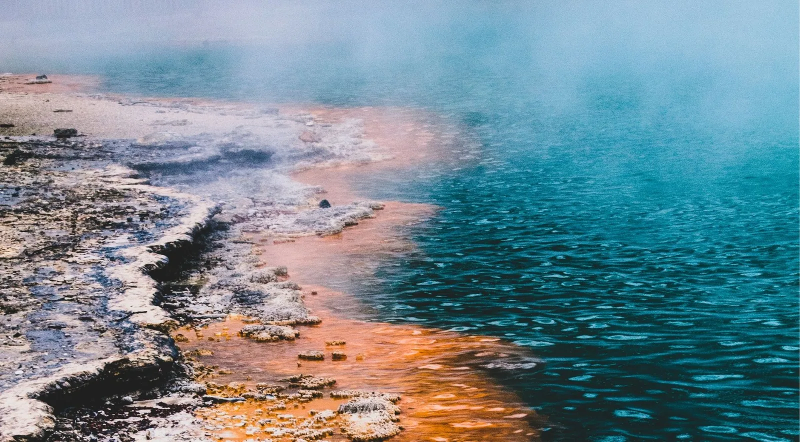 Turquoise geothermal water meeting an orange sinter shelf